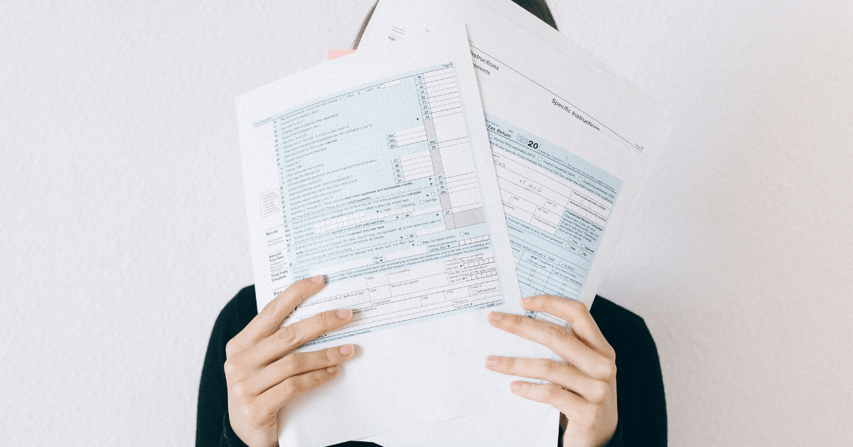 Person holding a stack of tax documents in front of their face.